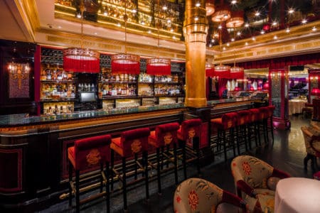A China club setting with a cocktail bar with golden features and red upholstered seating