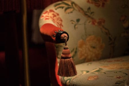 A close up of a tassel on a Park Chinois upholstered, highly decorated dining chair