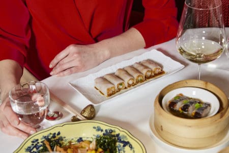 A lady with a red top, dining at Salon de Chine's table with Chinese spring rolls in Mayfair