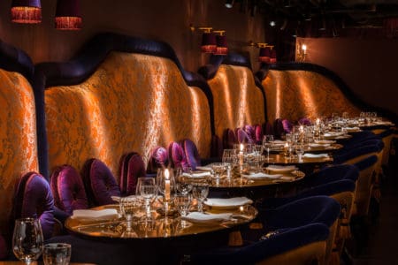 An empty luxury Chinese restaurant with velvet upholstery seats and wallpaper in London