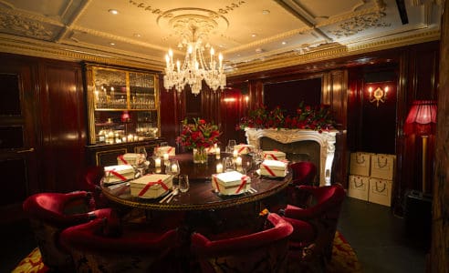 Wide angle view of a private dining room with shanghai décor and a hanging chandelier