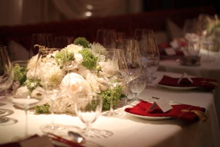 An up close view of luxury group dining room with a white table cloth and flowers in the middle
