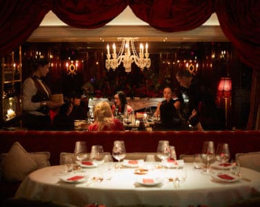 A high-end private dining table elegantly prepared, with a chandelier above in Salon Noir Bar